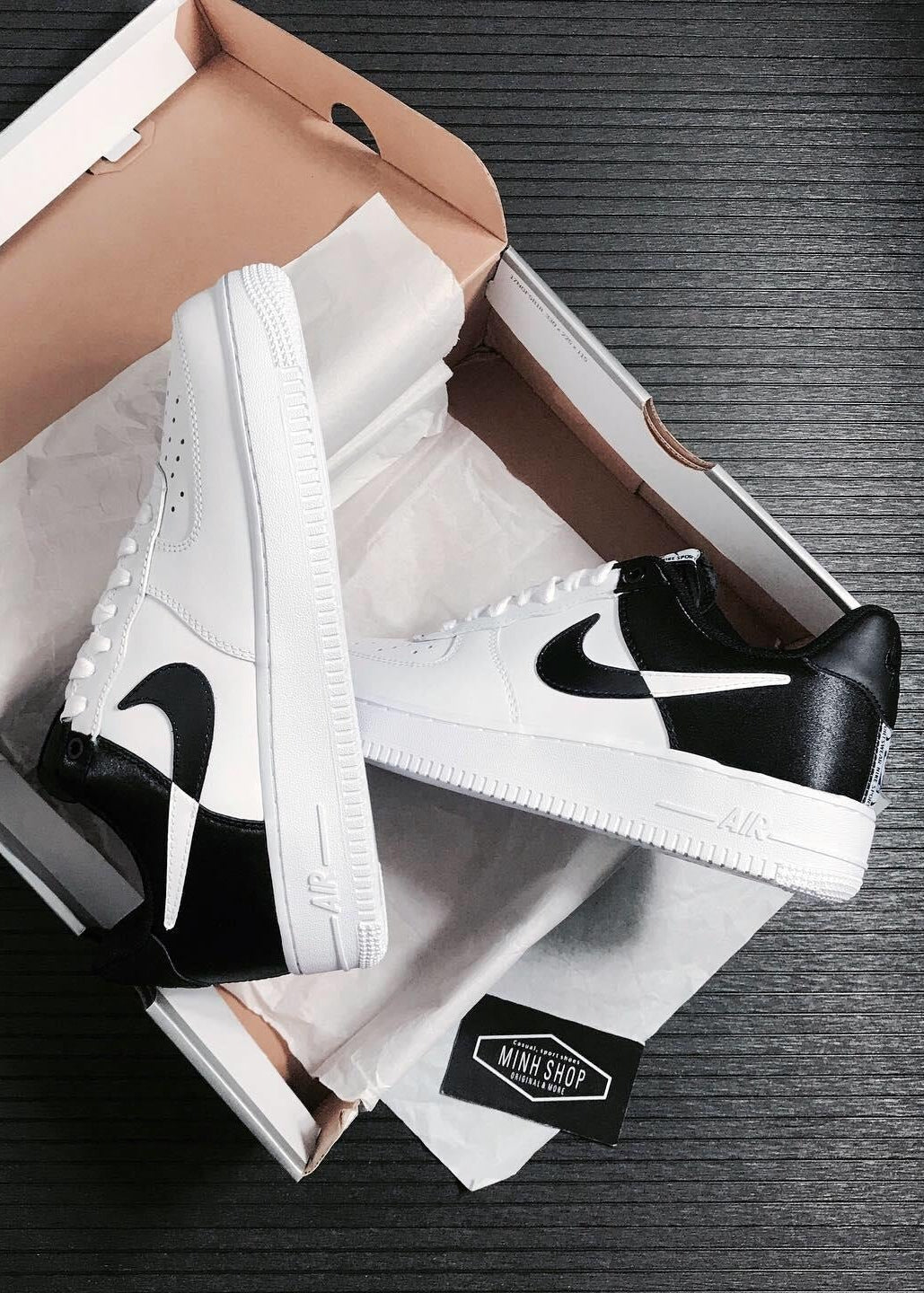 White sneakers with black swoosh logo in a box on a dark surface