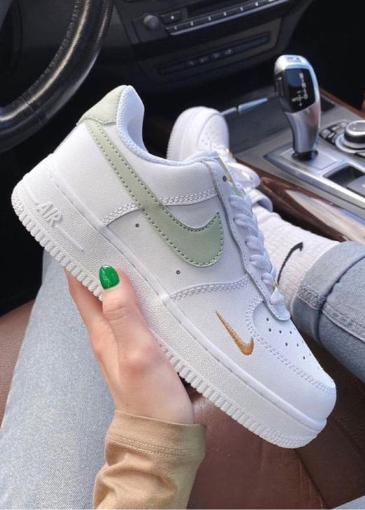 White and light green sneaker with Nike logo held by a person inside a car.