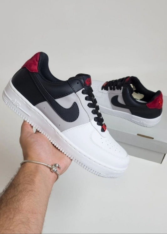Black, white, and red sneaker being held with a plain background
