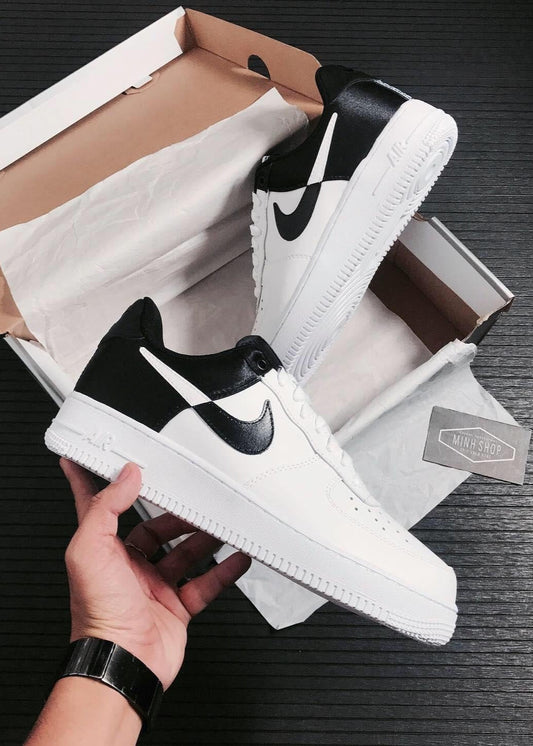 White and black sneakers with a Nike logo held above an open box on a dark surface.
